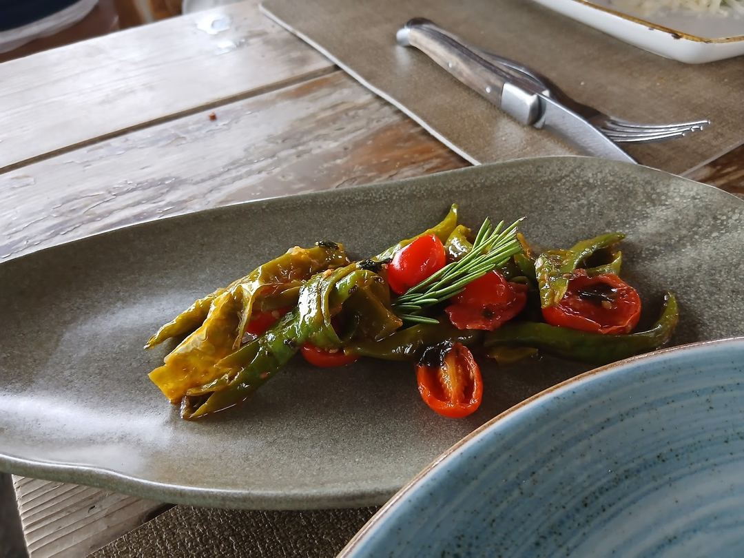 Grilled vegetables with rosemary garnish plated on a gray ceramic dish at the restaurant.